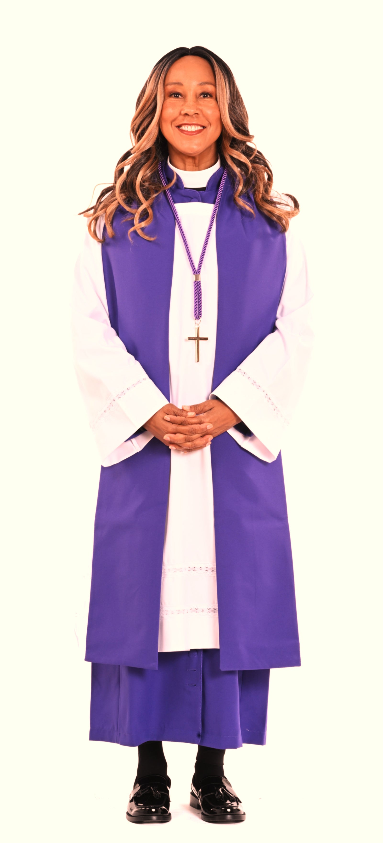 Women's Bishop Outfit & Attire featuring a smiling woman in purple clerical dress with a cross necklace.