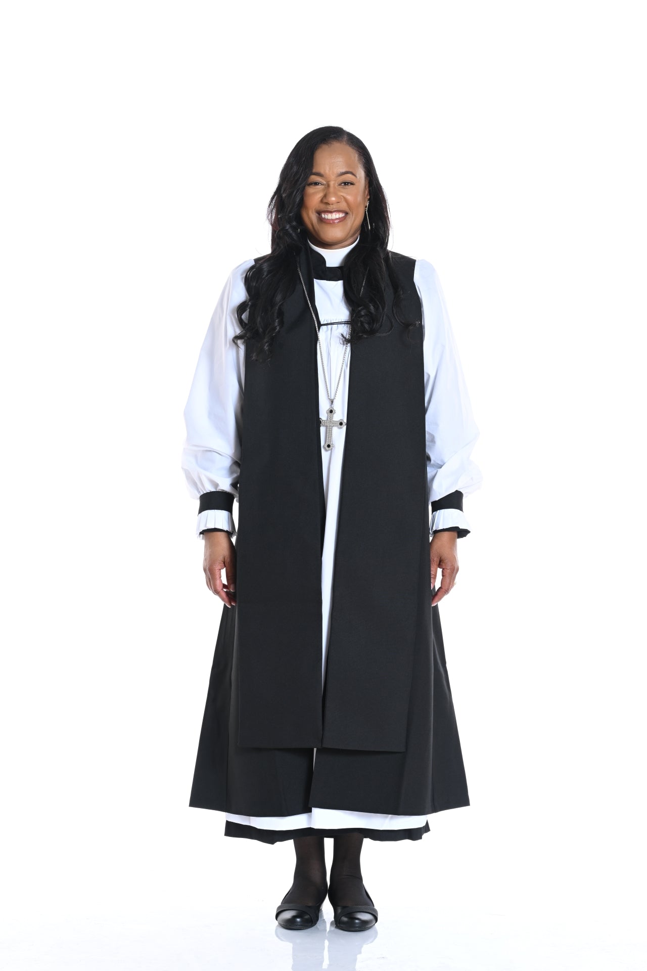 A smiling woman wearing Women's Pastor Robes & Attire, showcasing a stylish black robe over a white outfit.