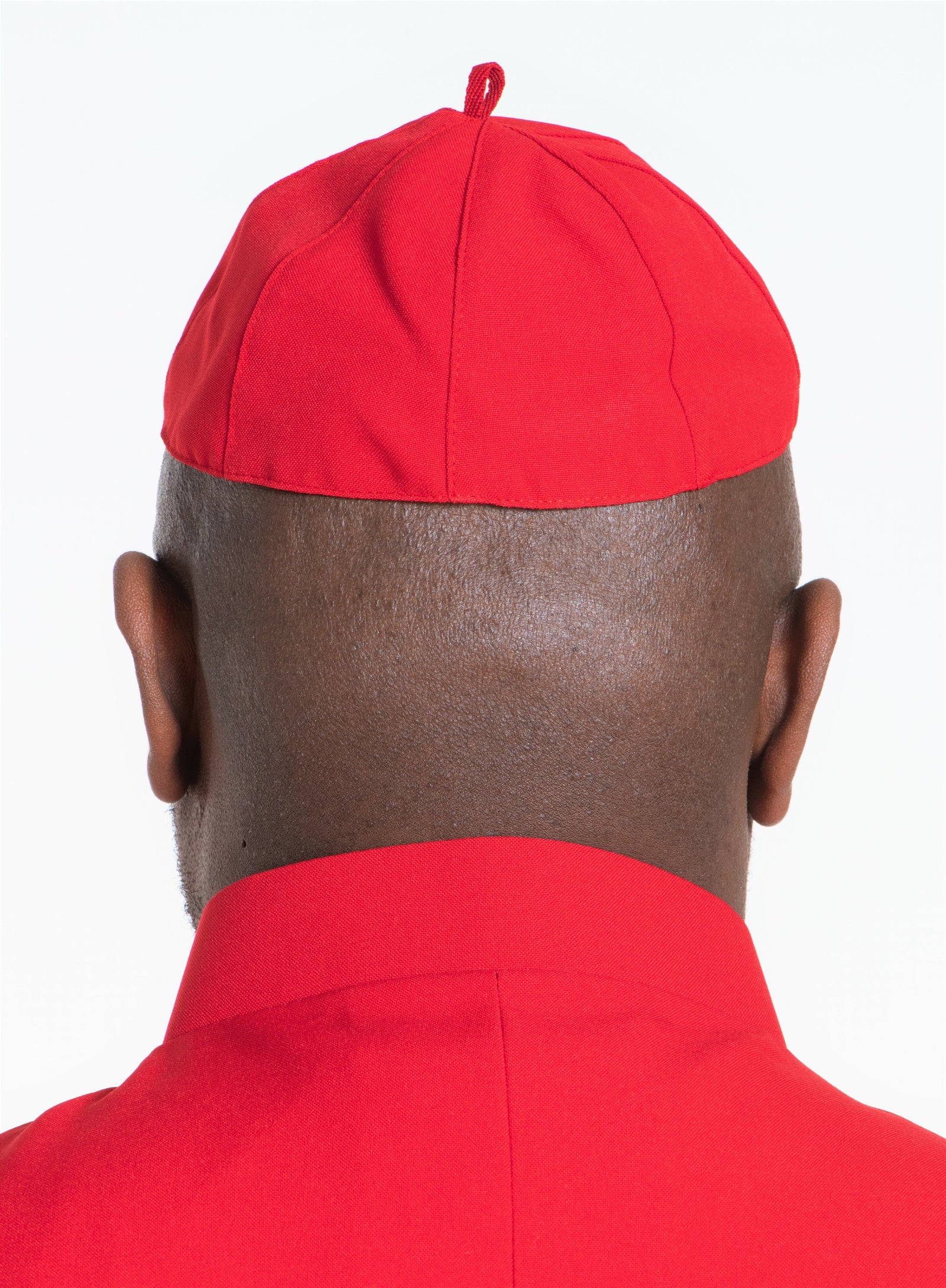 Back view of a person wearing a red zucchetto cap, showcasing the unique design and color of zucchetto caps.