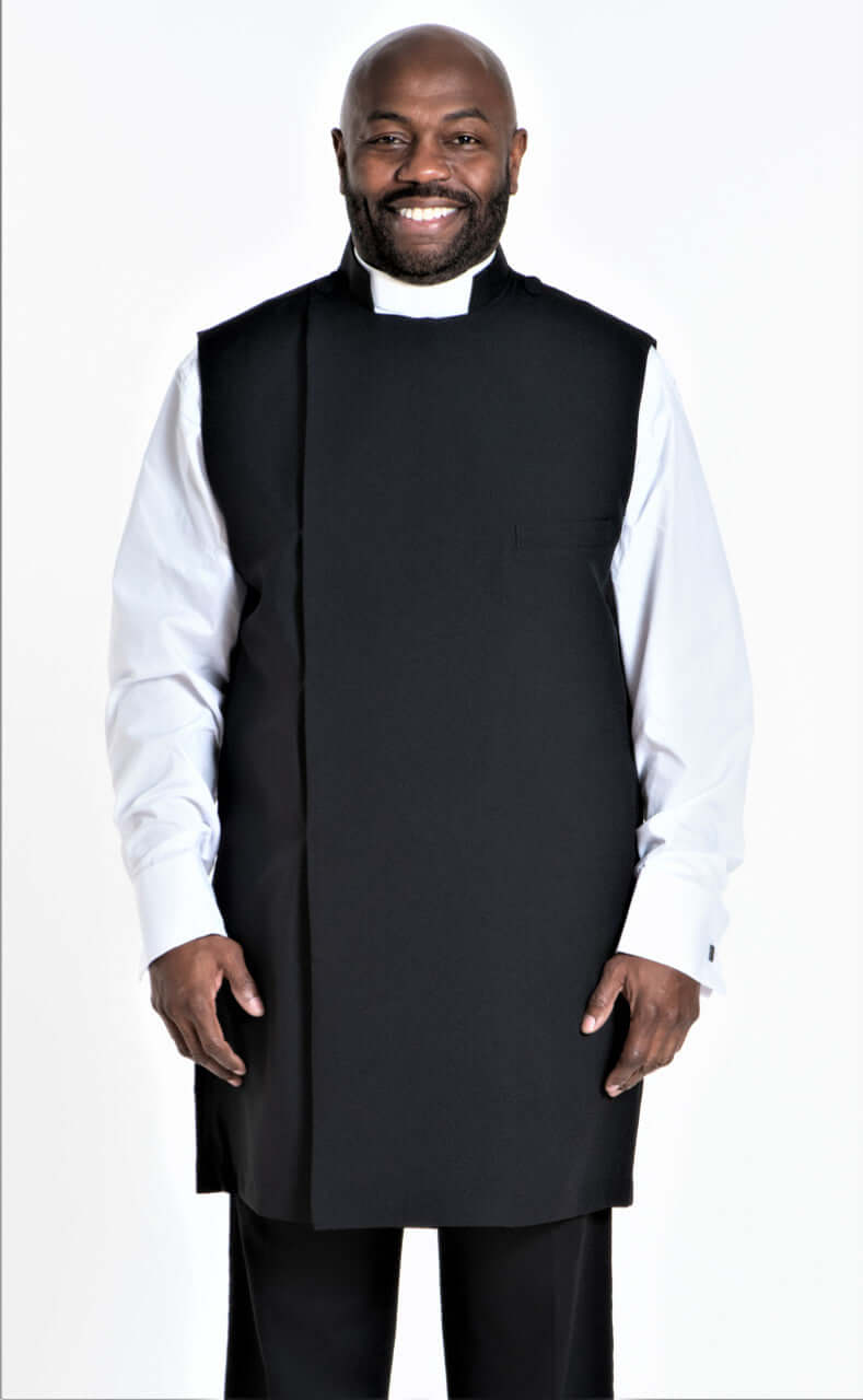Clergy Apron In Black worn by a smiling man, featuring a full cut fit and Anglican snap closure.