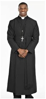 Smiling man in a black clerical robe and cross necklace, standing confidently, representing a religious figure.